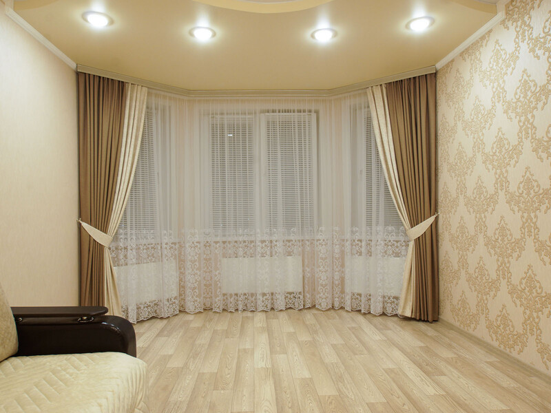 Бежевые шторы и кружевной тюль в классическом интерьере гостиной.